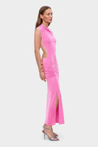Woman wearing a pink sleeveless Aya dress with cut-out design on a white background, back view