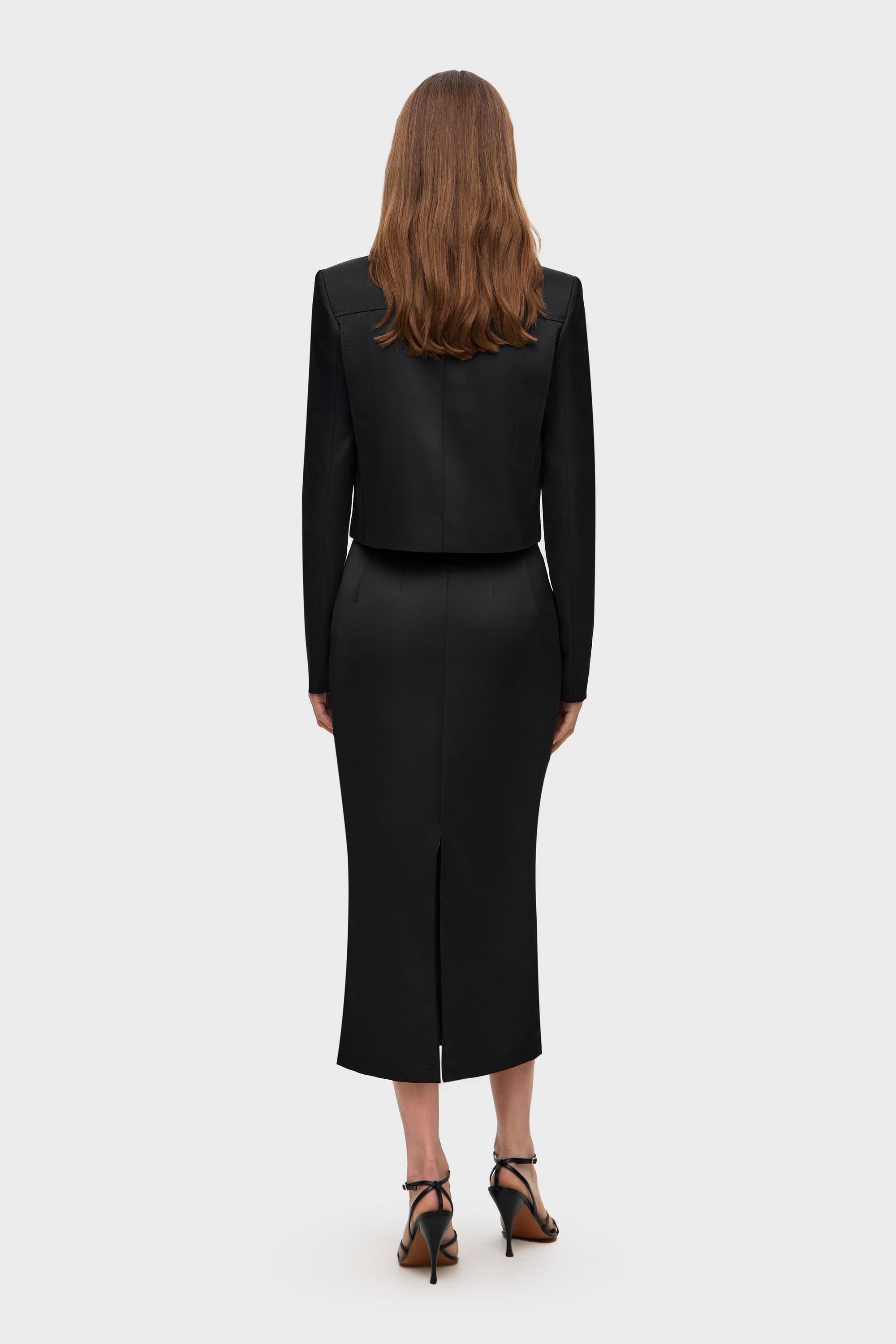 Woman wearing a black Kaya skirt on a white background, back view