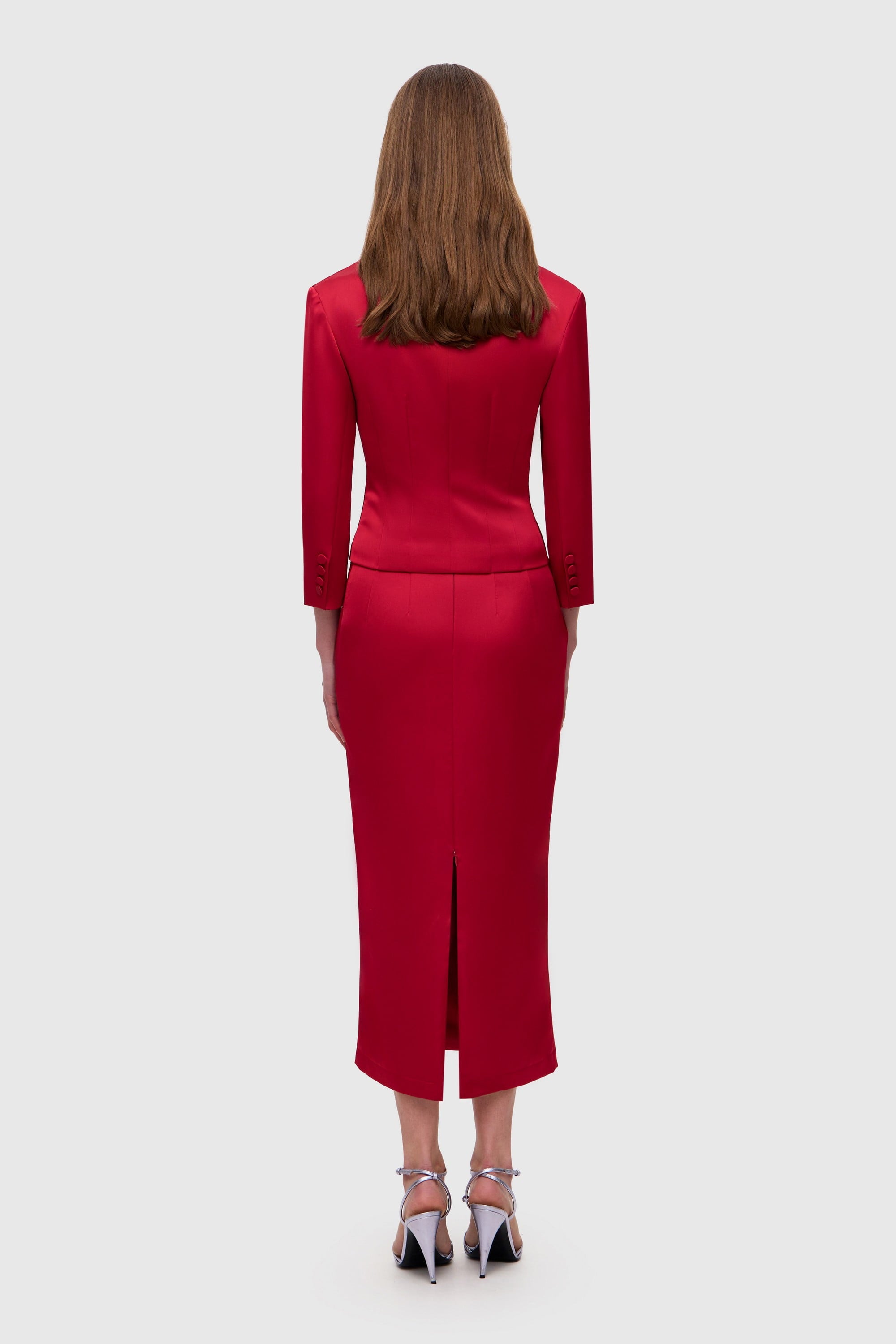 Woman wearing a red Kaya skirt on a white background, back view