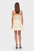 Woman wearing a ivory Mini Chloé dress with a corset top with stitching and wide skirt on a white background, back view